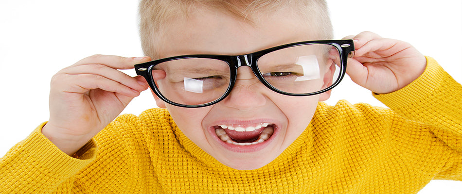 Ein Kind trägt einen gelben Pullover und hält sich eine große schwarze Brille auf die Nase. Es hat einen wütenden Gesichtsausdruck und schreit.