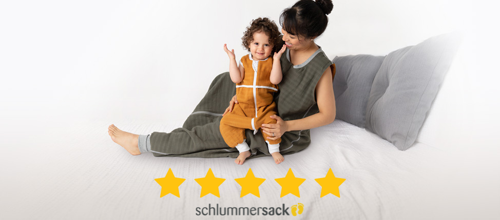 Mutter und Kind in passenden Schlummersack-Schlafsäcken, beide lächelnd, darunter fünf gelbe Sterne.