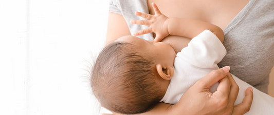 Eine Mutter stillt ihr Baby, das an ihrer Brust trinkt.