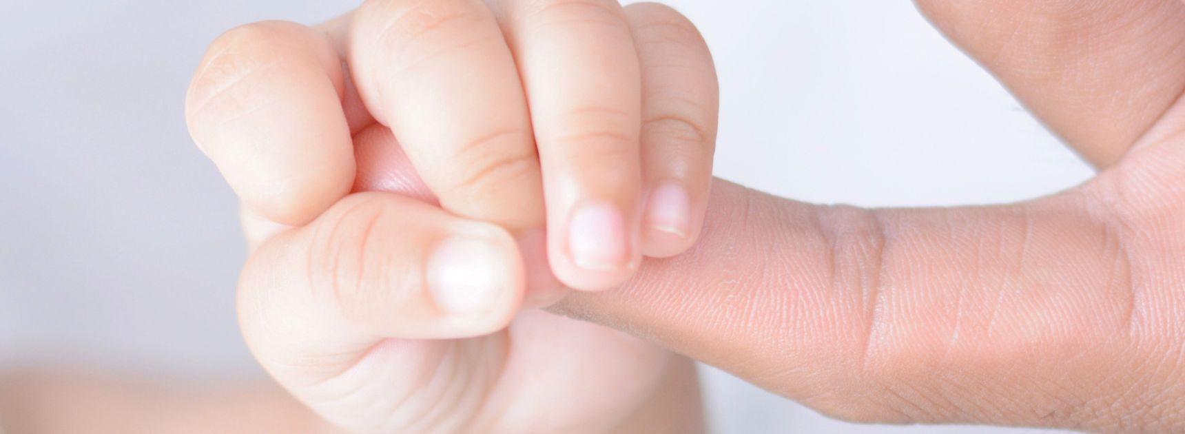 Baby hält Finger der Mutter