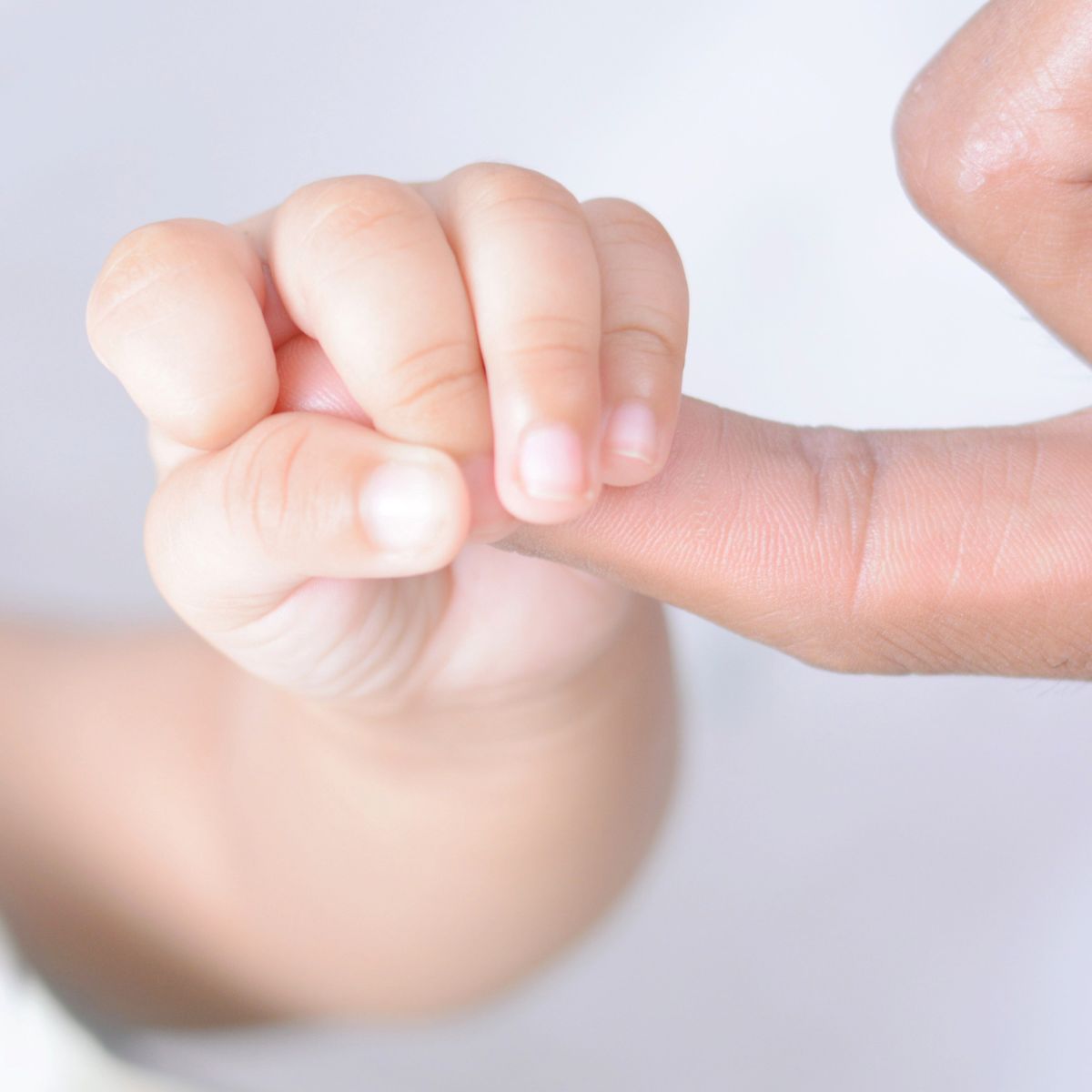 Baby hält Finger der Mutter